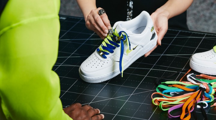 A salesperson holding a white sneaker with multicoloured laces.