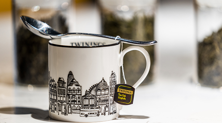 A black and white Twinings ceramic mug with a whimsical London street scape printed on it.