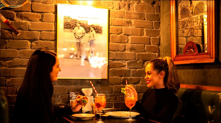two girls drinking cocktails in a bar