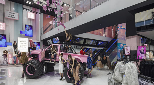 Fashionable mannequins draped over a pink four-wheel drive.
