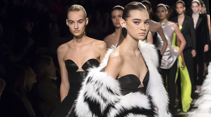 A close up of glamorous women in black and white gowns on the runway.