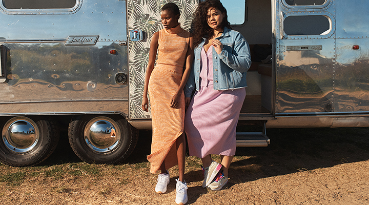 Two models standing in front of an Airstream caravan.
