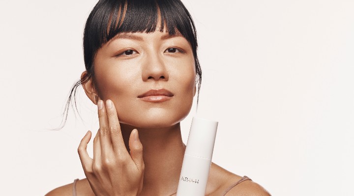 An Asian woman in a skincare campaign holding a product.
