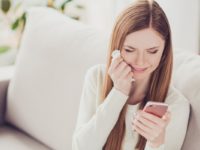 woman crying while looking at mobile phone