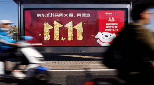 People ride on a scooter past a JD.com ad promoting Singles Day shopping festival, in Beijing, China.