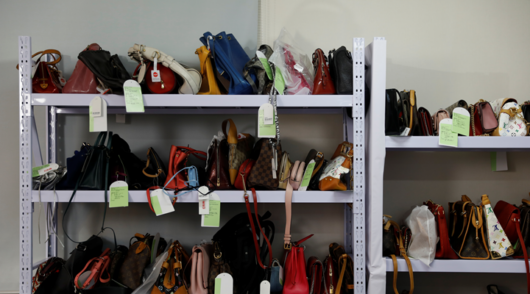 a rack with dozens of luxury bags with price tags