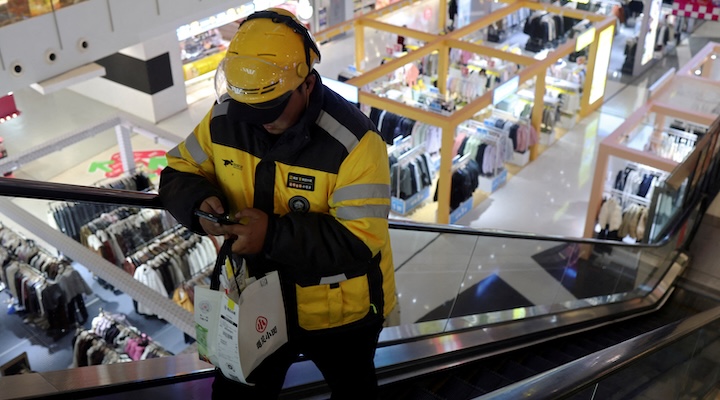 A Meituan delivery worker picks up a food order at a shopping mall in Beijing.