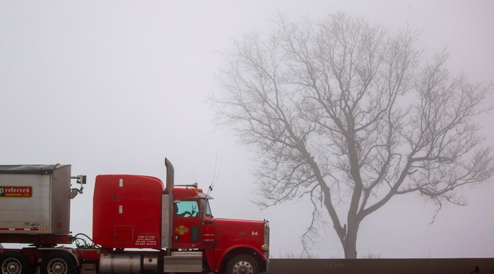 Red truck on misty highway.