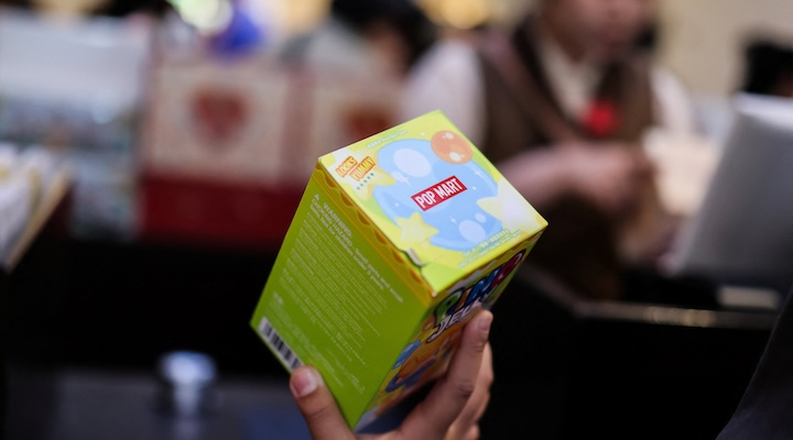 A boy holds a branded box with a toy next to a cashier at the Pop Mart store at the company’s Pop Land theme park on its reopening day after an upgrade