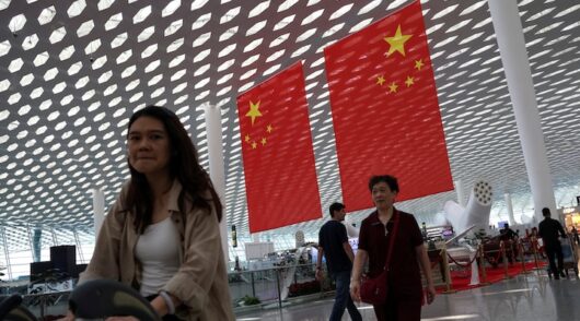 People walk past giant Chinese national flags hung at the Shenzhen Bao'an International Airport