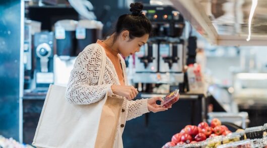 Asian woman choosing fresh fruits in an indoor supermarket setting